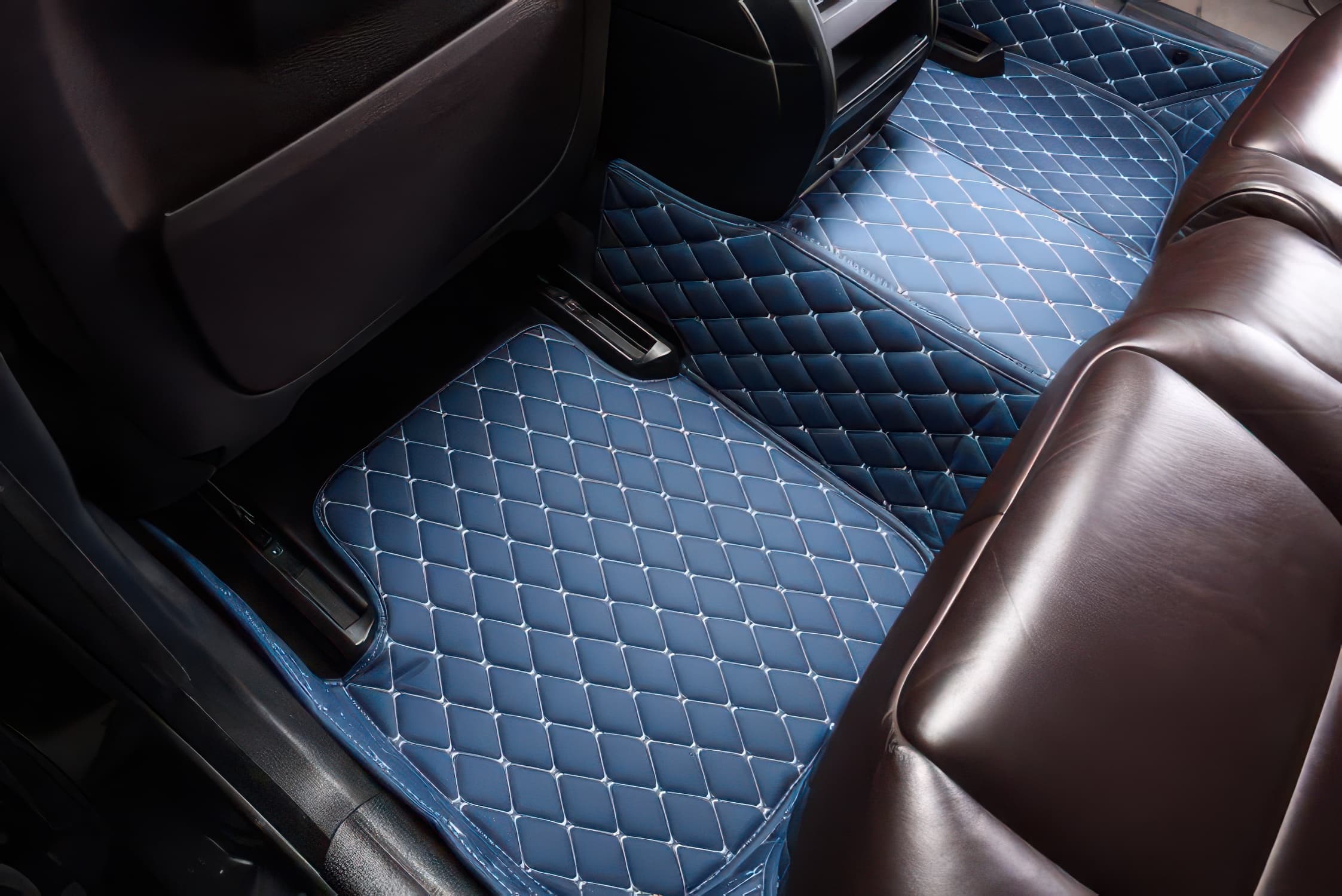 Car interior with blue car mats and brown leather seats.